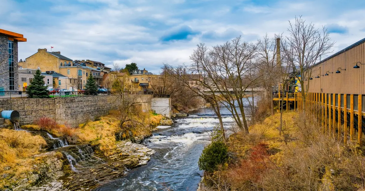 The Grand River flowing past historic Ontario stone buildings upstream of Cambridge, home of payday loans Cambridge borrowers
