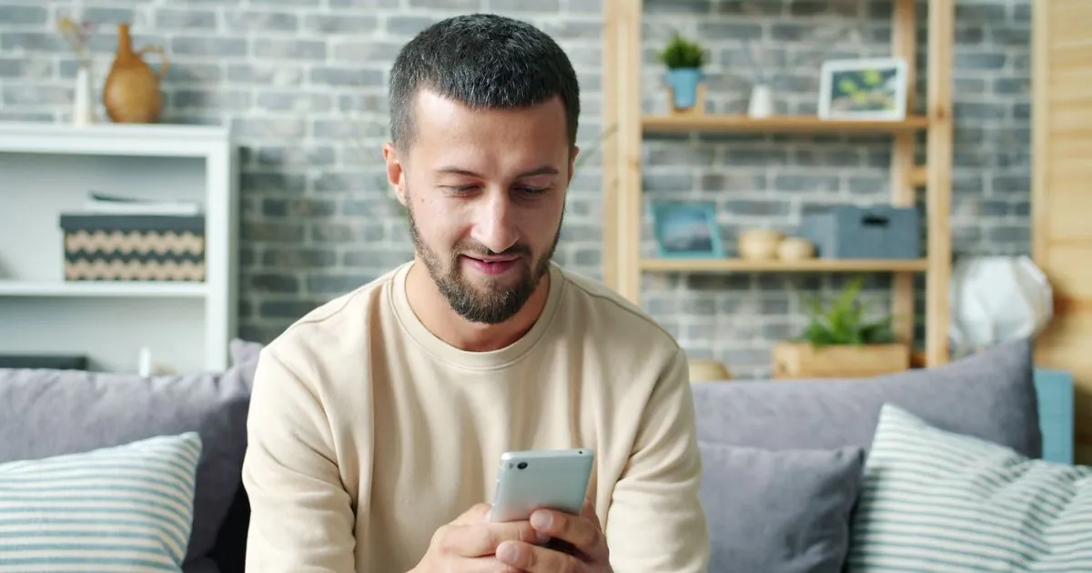Man checking the Canadian bank account his pay goes into on his phone at home