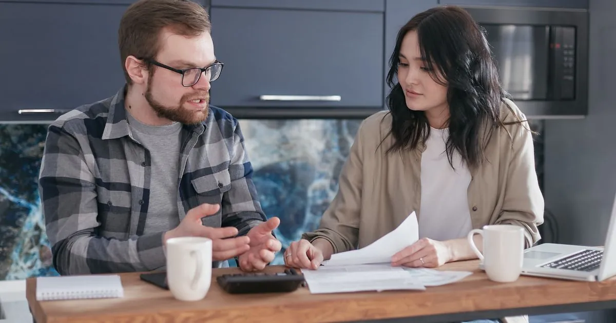 Couple at a kitchen table working out a payday loan cost before borrowing in Canada