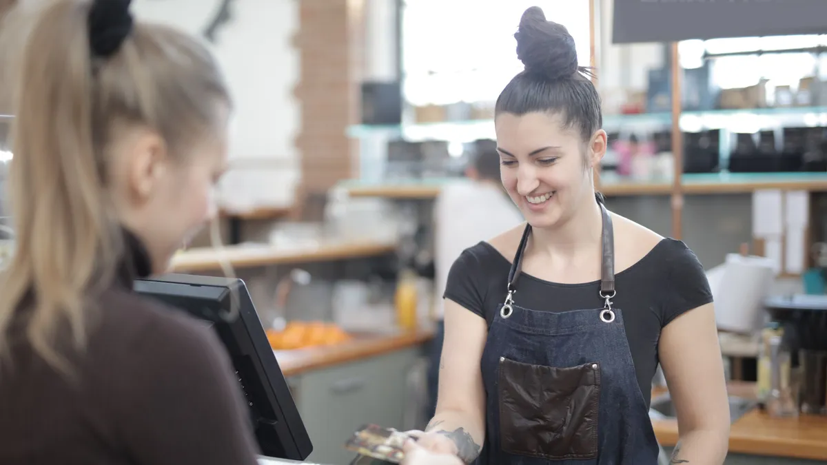 Customer paying a small bill by card at a cafe counter, the kind of gap a $300 payday loan covers