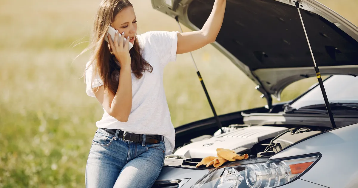 Driver on the phone beside her car with the hood up, the kind of repair bill a $500 payday loan in Canada covers