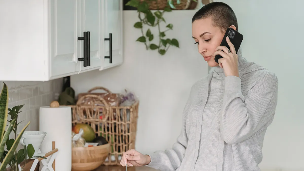 Woman on the phone in her kitchen confirming her pay dates for a $500 payday loan
